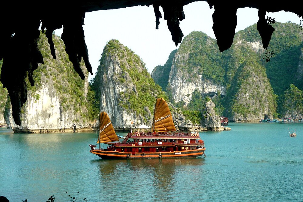 Traditional junk boat entering a cave in Ha Long Bay