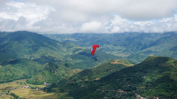 A paraglider over Lim Mong village and the Cao Pha valley, seen from Khau Pha Pass