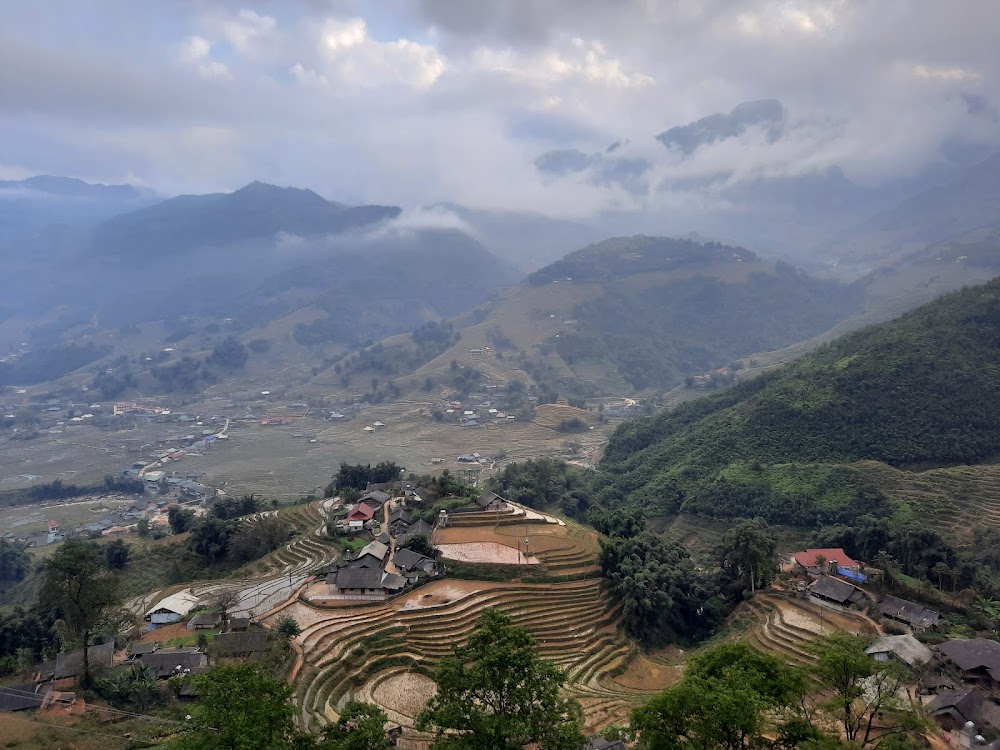 A hillside village above harvested terraces under winter cloud in Mu Cang Chai in December