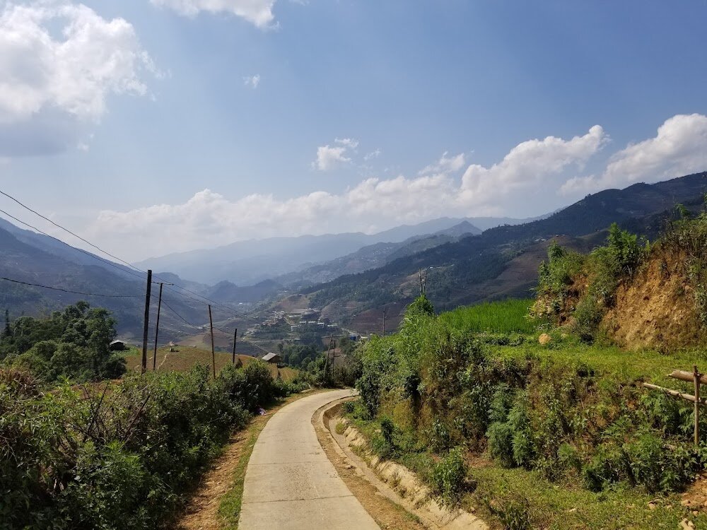 A village road past young green rice terraces in Mu Cang Chai in May
