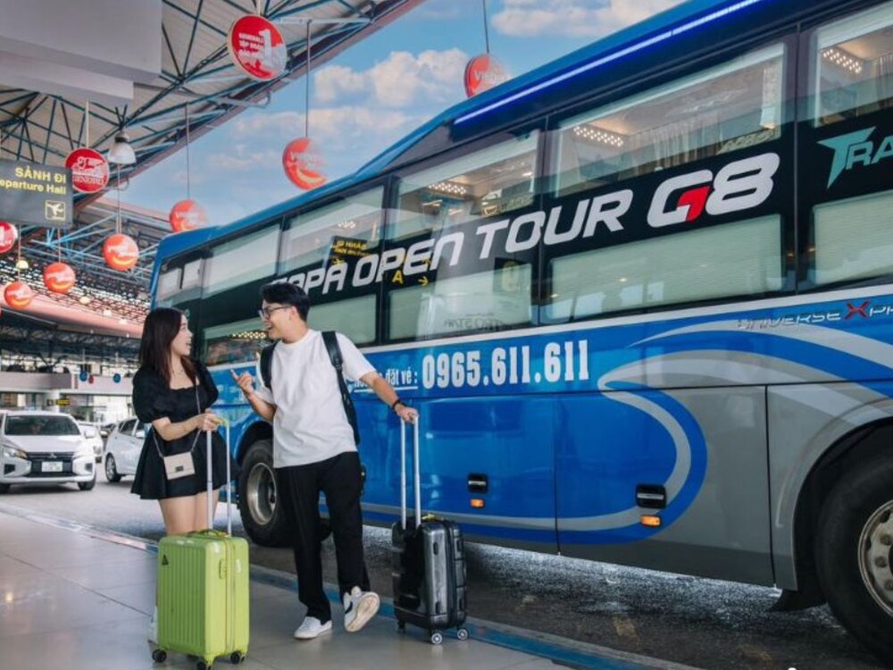 Two travellers with luggage boarding a sleeper bus at a Hanoi bus terminal