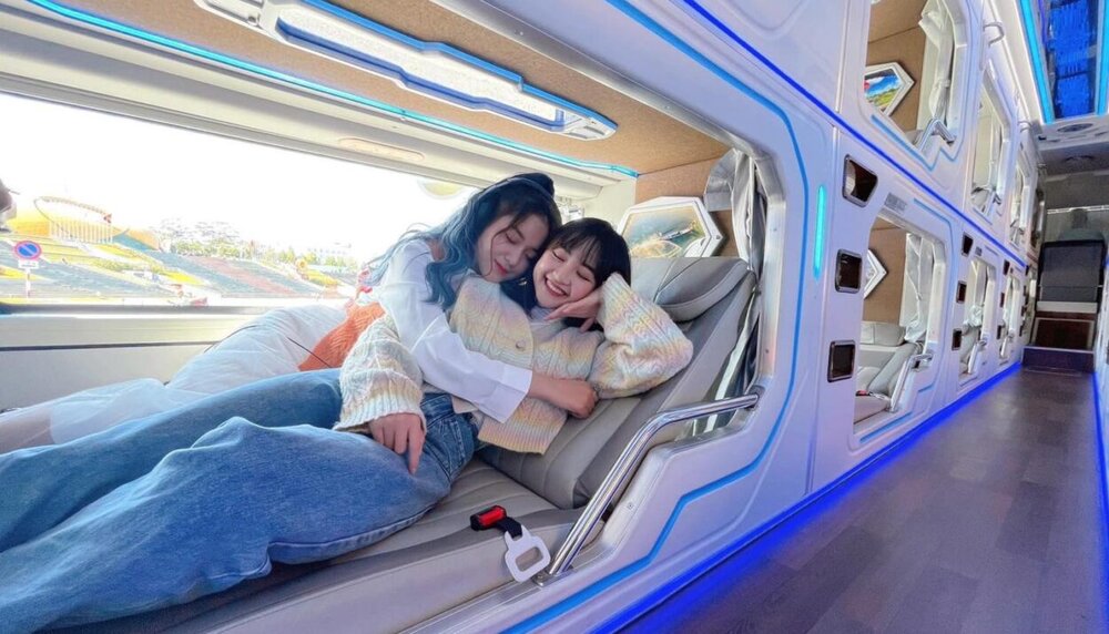Two passengers resting in a double VIP cabin pod on a sleeper bus from Ho Chi Minh City to Da Lat