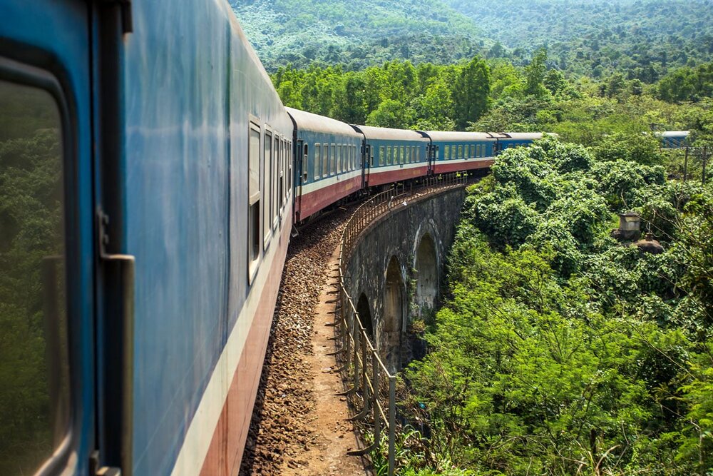 Reunification Express crossing a colonial-era viaduct through jungle between Hue and Da Nang